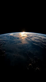 Sunlit Earth horizon from space with low cloud formations visible.