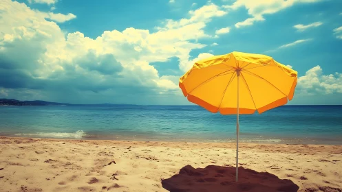 Yellow beach umbrella on quiet shoreline under clouds.