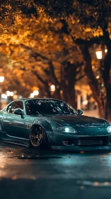 Modified teal sports coupe idles under autumn streetlights at night