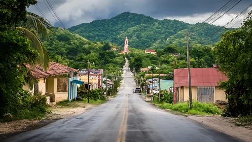 Straight village road leading toward hilltop church tower.