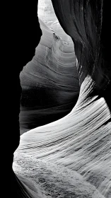 Monochrome narrow canyon with curved layered rock walls.