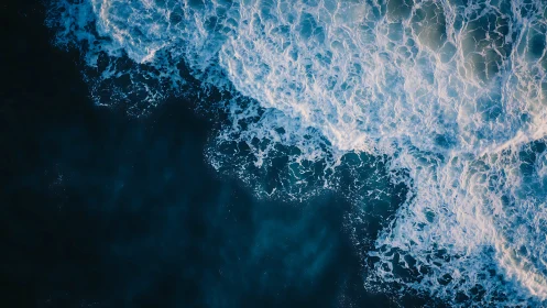 Crashing ocean waves churn against deep blue open water