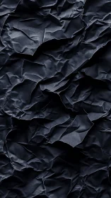 Crumpled dark textile surface forms abstract tonal topography