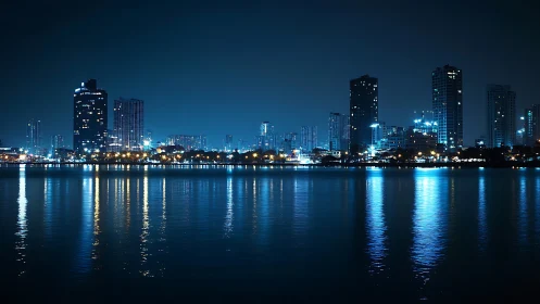 City waterfront skyline at night with blue reflections.