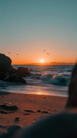 Golden sunset glows over tranquil waves on a rocky shore