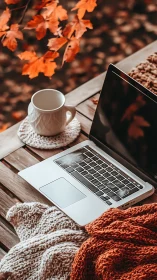 Cozy laptop workspace rests among warm autumn leaves outdoors