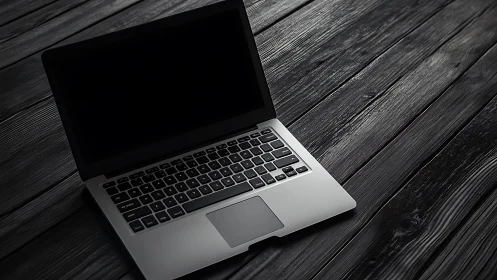 Sleek silver laptop rests on dark textured wooden desk
