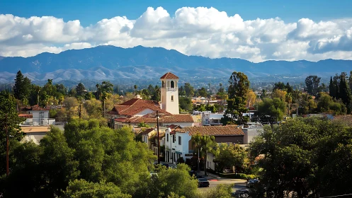 Sunlit hillside town with tiled rooftops and distant mountains.