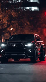 Midnight black SUV prowls through neon city streets.