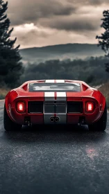 Rear low-angle study of classic red sports car on wet mountain road