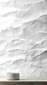 Minimalist bowl rests before sculpted white relief wall.