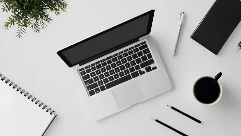 Open laptop anchors minimalist white creative workspace