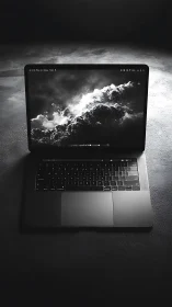 Open laptop on dark textured surface under overhead light.
