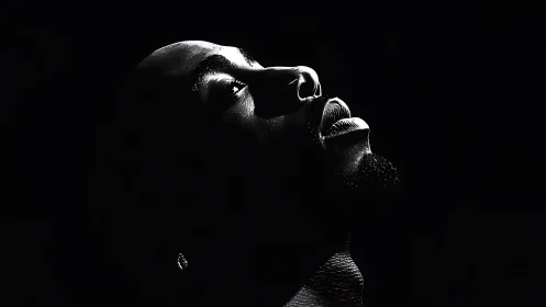 Side-lit male portrait in deep black negative space.