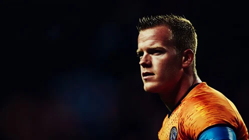 Focused male soccer player in bright orange jersey.