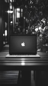 Laptop with illuminated logo sits centered on outdoor table