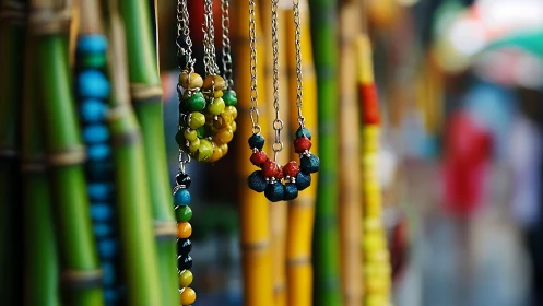 Colorful beaded necklaces hang against blurred bamboo stall