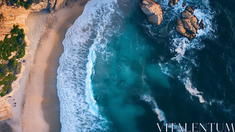 Aerial shoreline captures turquoise surf and sunlit rocks.