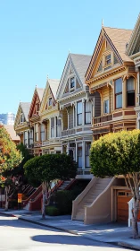 Painted Victorian houses glow under clear blue sky.
