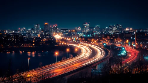 Urban night skyline with highway light trails and river.