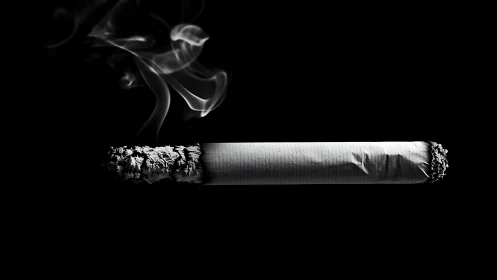 Burning cigarette floats in darkness while ghostly smoke curls