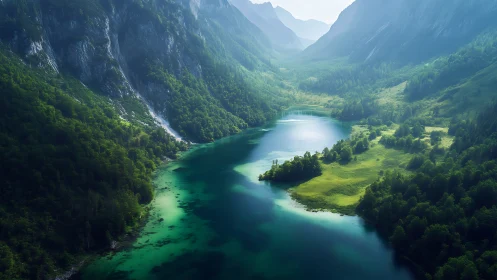 Emerald alpine lake winding through misty mountain valley.
