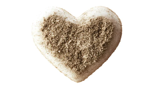 Heart-shaped object coated with granular beige and tan powder.
