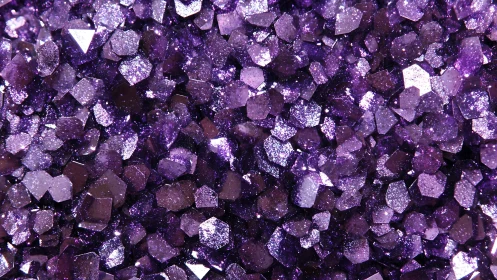 Macro capture of faceted violet glitter particles with specular highlights