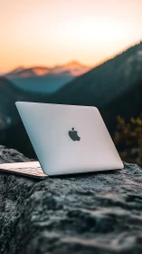 Nomad laptop glows against ember-tinted mountain dusk.