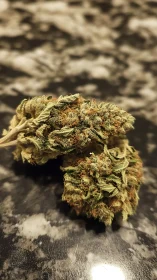 Close-up of cannabis buds on a dark marble surface.