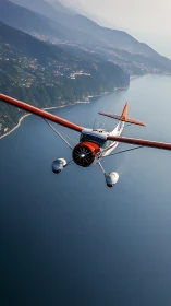 Vintage seaplane glides above tranquil coastal lake shoreline.