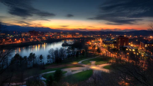 Urban riverside cityscape at dusk with illuminated streets.