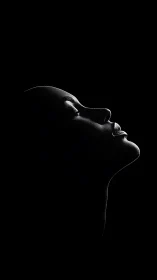 Side profile silhouette of human face in low key light.