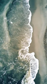 Vertical aerial view of shoreline with breaking sea waves.