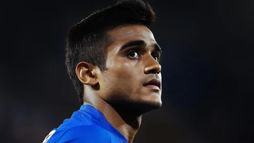 Focused football player in blue jersey under stadium lights.