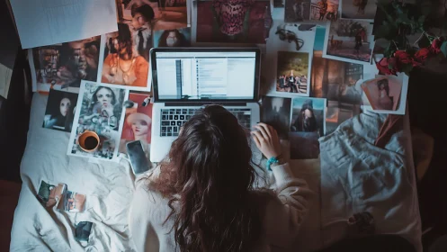 Overhead view of photographer editing images on laptop in bed
