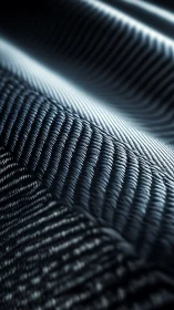 Macroscopic braided carbon fiber surface under cool light.