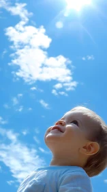 Smiling toddler looking upward under bright blue sky.