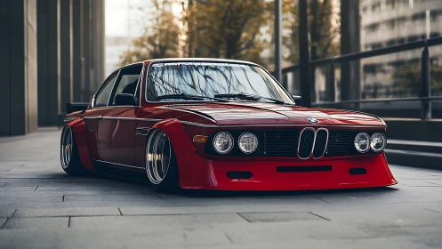 Sleek classic red BMW coupe rests low in a modern city lane