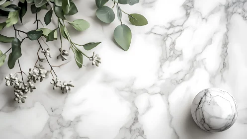 Marble sphere and foliage on bright veined countertop.