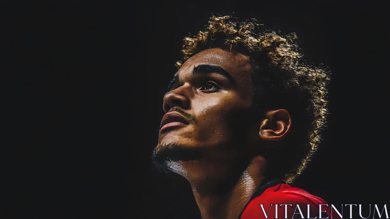 Focused young athlete gazes upward under dramatic spotlight.