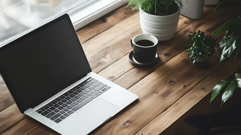 Laptop with coffee and plants sit on wooden desk surface