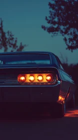 Rear view of vintage muscle car with glowing tail lights at dusk