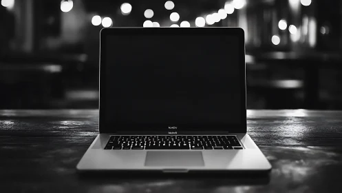 Open laptop glows softly in a dimly lit modern cafe.