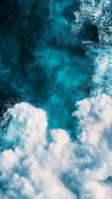 Aerial ocean foam churns over deep turquoise water surface.