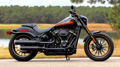 Low-slung black cruiser motorcycle beside tranquil lakeshore.