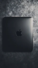 Sleek Black MacBook Pro on Textured Concrete Surface.