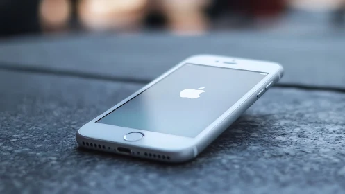 White iPhone with Glass Retina Display on Textured Concrete Surface