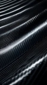 Gently rippled carbon fiber catching soft silver light.