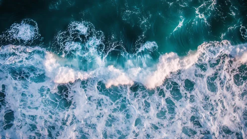 Aerial view of breaking turquoise ocean surf waves.